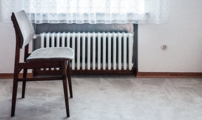 Energieausweise erstellen alte Wohnung mit Stuhl vor Heizung