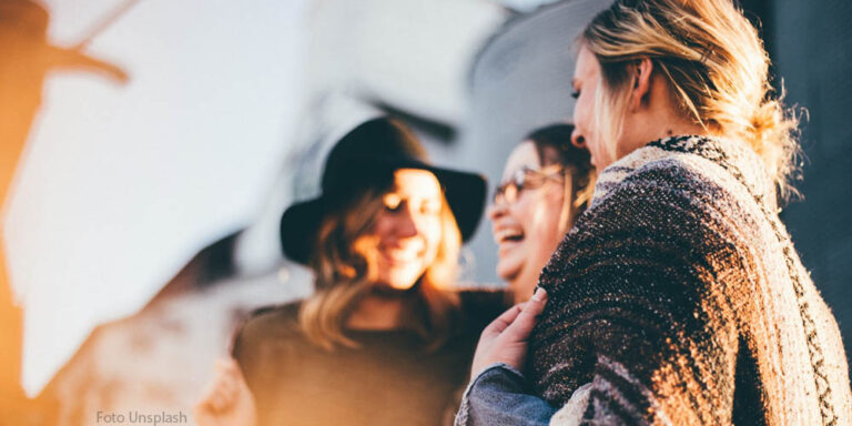 Frauen stehen zusammen und lachen entspannt - Psychologische Sicherheit