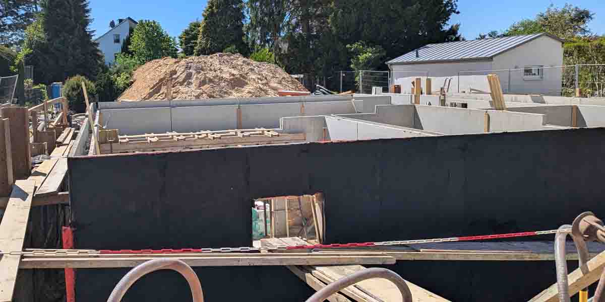 Kellerwände im Rohbau mit einer aufgetragenen schwarzen Bitumenabdichtung